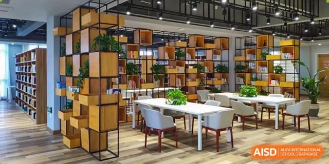 A bright, modern study or reading area at Shanghai New Epoch Bilingual School library with white furniture and floor-to-ceiling bookshelves.