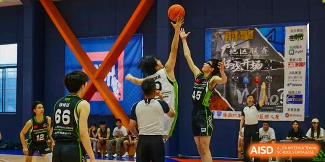 Two players from Shanghai New Epoch Bilingual School jumping for a basketball during a game, with a referee watching nearby.