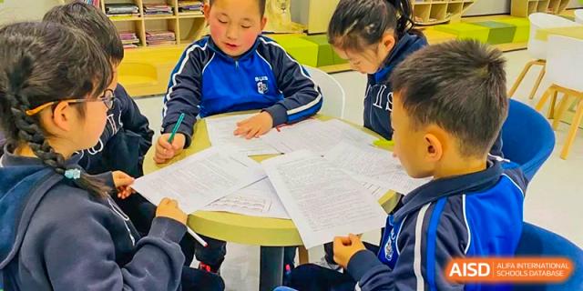A close-up of students working together, reviewing and marking large stacks of paper or exam sheets at Shanghai United International School, Wanyuan Campus.