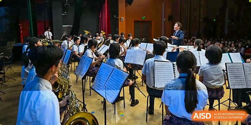 Students in an orchestra or band playing their instruments and reading music from stands at Shanghai United International School, Wanyuan Campus.