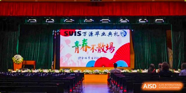 A stage setup for the SUIS Wanyuan Graduation Ceremony, with a screen displaying Chinese text that translates to "Youth Will Never End" at Shanghai United International School, Wanyuan Campus.