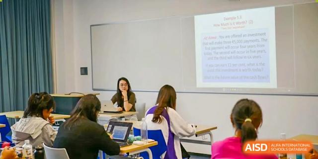 A student from SHENGHUA ZIZHU ACADEMY seated at a desk, engaging in a classroom session with a teacher or another student.