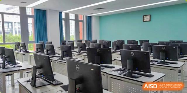 A well-equipped computer lab at SHENGHUA ZIZHU ACADEMY with rows of workstations and large monitors.