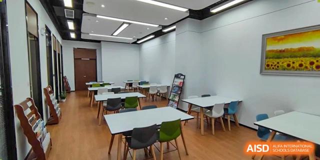A bright classroom or discussion space at SHENGHUA ZIZHU ACADEMY with white walls, multiple small tables, and modern black and white chairs.