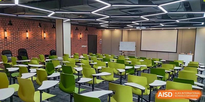A modern lecture hall or classroom at SHENGHUA ZIZHU ACADEMY with tiered seating in bright green and an interesting geometric ceiling light design.