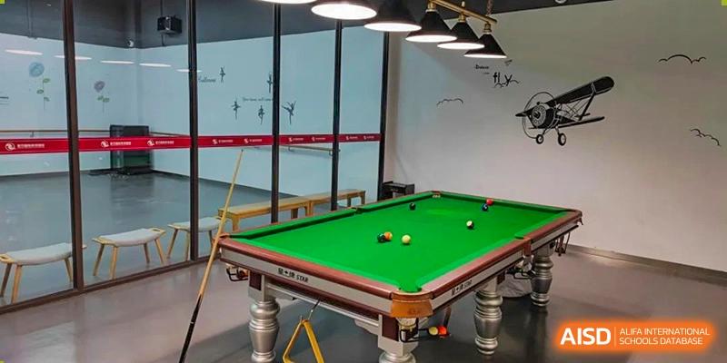 An interior view of a recreation area at SHENGHUA ZIZHU ACADEMY, featuring a full-sized green billiards or pool table.