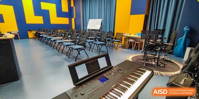 An electronic keyboard and black chairs set up in a music practice room or performance space at SHENGHUA ZIZHU ACADEMY.