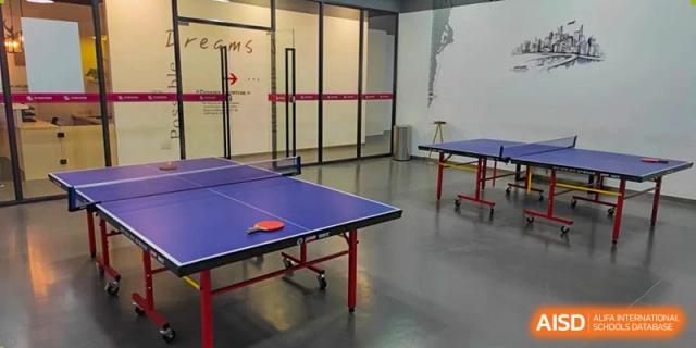 An indoor recreation room at SHENGHUA ZIZHU ACADEMY with a blue ping pong or table tennis table.