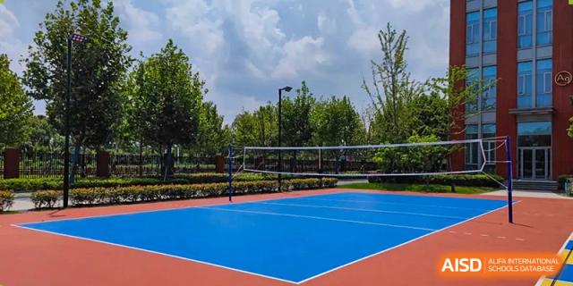 An outdoor blue sports court, possibly for tennis or basketball, surrounded by a chain-link fence and trees at SHENGHUA ZIZHU ACADEMY.