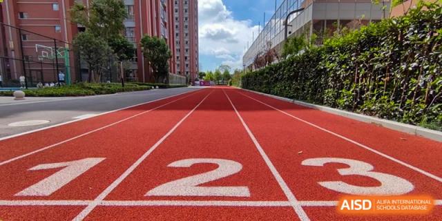 A close-up of the bright red, synthetic running track with lane number '2' prominently marked at SHENGHUA ZIZHU ACADEMY.
