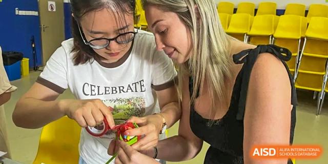 A teacher helping students with a hands-on puzzle or building activity at Shenzhen American International School.