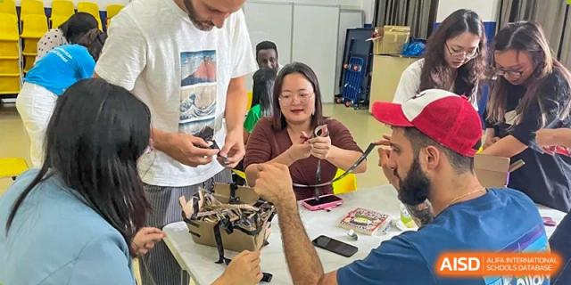 Adults and students collaboratively working on a hands-on craft or project at Shenzhen American International School.