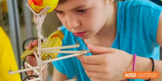 A young student carefully working on a small wooden craft or engineering project at Shenzhen American International School.