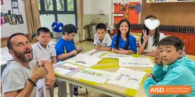 Students seated at a table, looking at educational materials or books together at Shenzhen American International School.