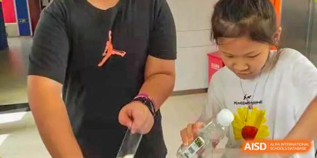 A close-up of a person wearing a Jordan t-shirt and handing a small item to another person at Shenzhen American International School.