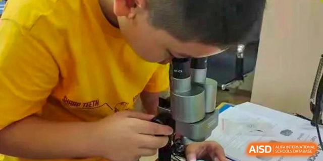 A close-up of a student looking through a microscope in a science lab at Shenzhen American International School.