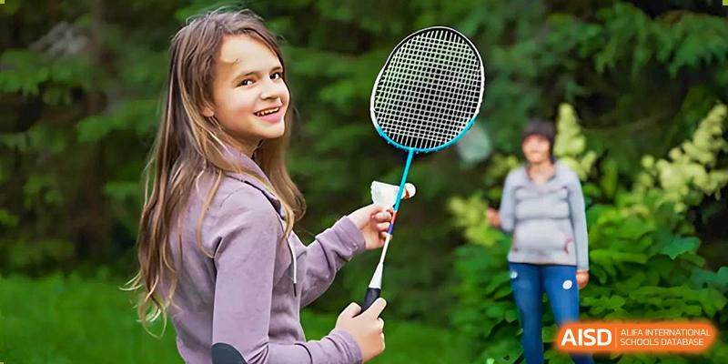 A young girl smiling and holding a badminton racket and shuttlecock at Shenzhen American International School.