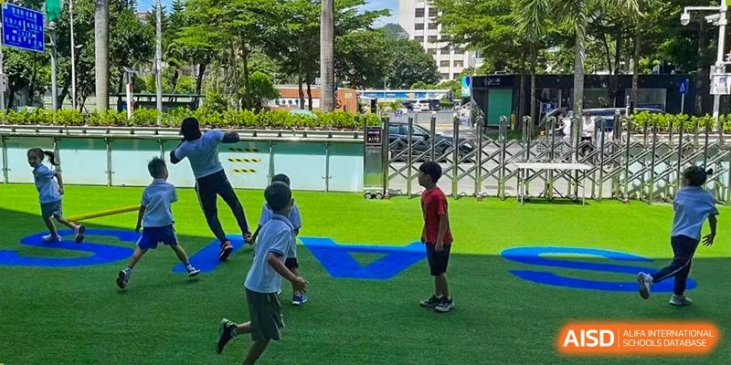 Students participating in an outdoor sports or play activity on a green turf field at Shenzhen American International School.