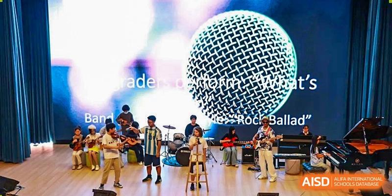 A group of students performing in a school rock band with a microphone in the foreground at Shenzhen American International School.