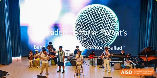 A group of students performing in a school rock band with a microphone in the foreground at Shenzhen American International School.