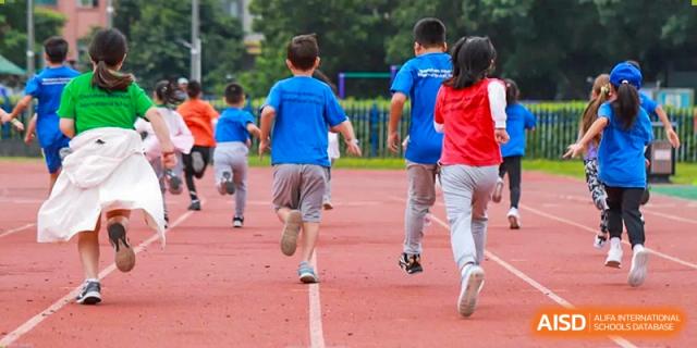 A group of students running on a red track during a race or physical education class at Shenzhen American International School.