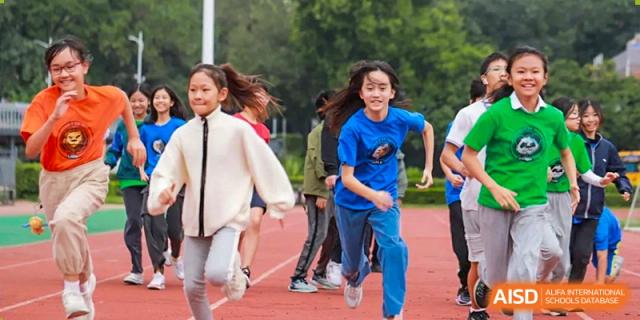A female student running and smiling during an outdoor sports activity at Shenzhen American International School.
