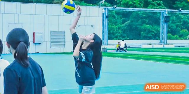A girl jumping to hit a volleyball during an outdoor sports class at Shenzhen American International School.