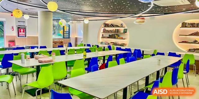 An empty dining area in the school canteen with bright green and blue chairs at Shenzhen American International School.