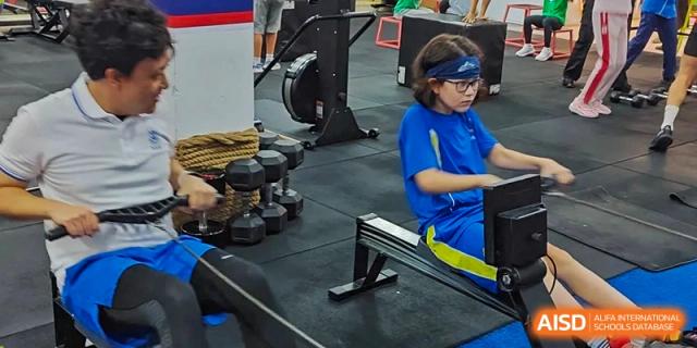 A young student wearing safety glasses and using fitness equipment in the school gym at Shenzhen American International School.