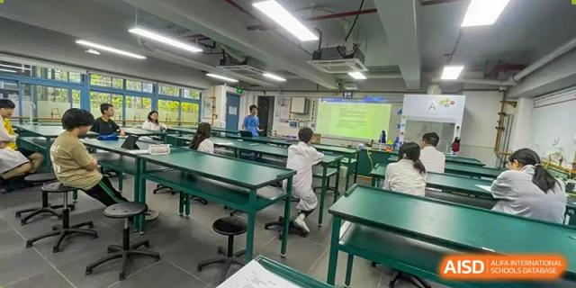Students working in a science laboratory with green desks and equipment at Shenzhen College of International Education.