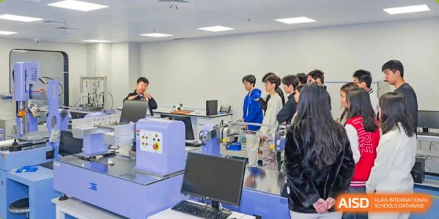 Students gathered around a computer and equipment for a lab or technical session at Shenzhen College of International Education.