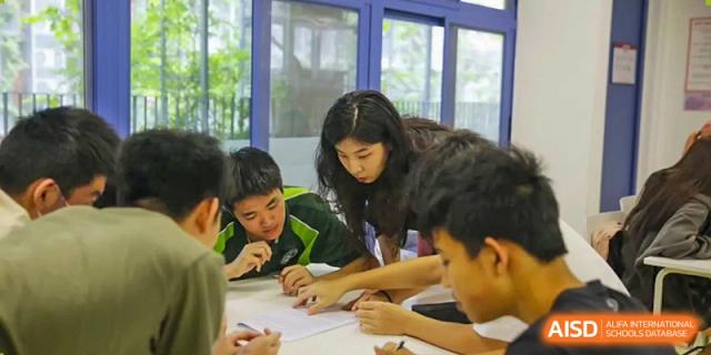 Students collaborating intently on a hands-on project around a table at Shenzhen College of International Education.