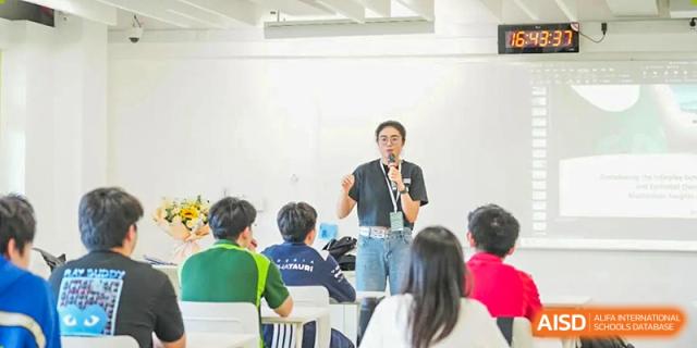 A teacher talking to students who are seated at desks during a class discussion at Shenzhen College of International Education.