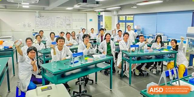 A large group of students in white lab coats posing in a science laboratory at Shenzhen College of International Education.