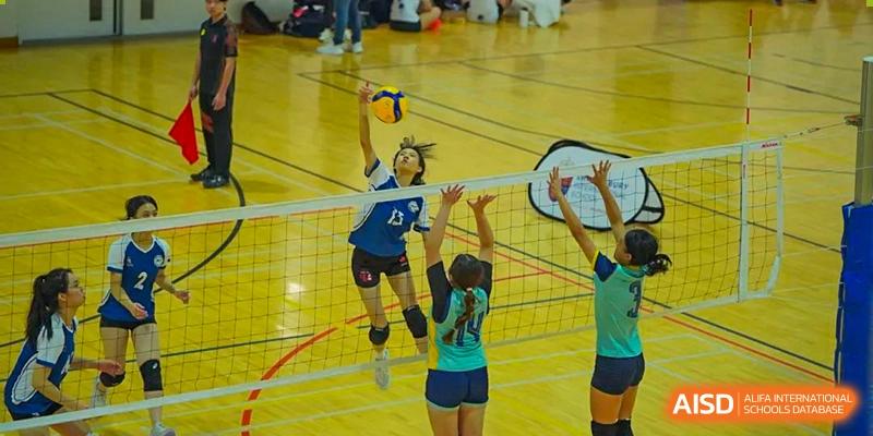 A female student jumping to spike a volleyball over the net during a game at Shenzhen College of International Education.