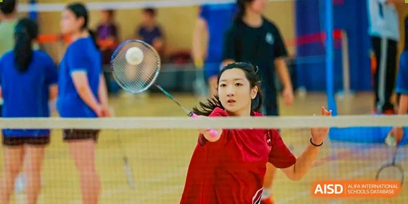 A female student focused on the net while playing a close-up shot of badminton at Shenzhen College of International Education.
