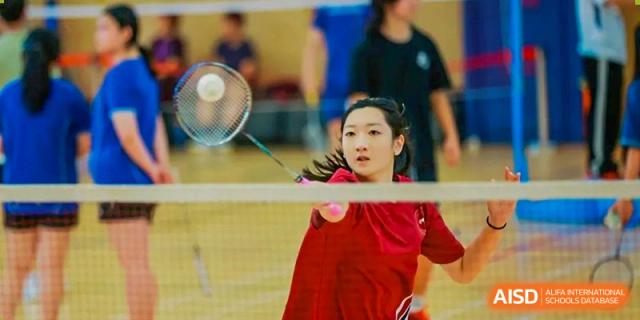 A female student focused on the net while playing a close-up shot of badminton at Shenzhen College of International Education.