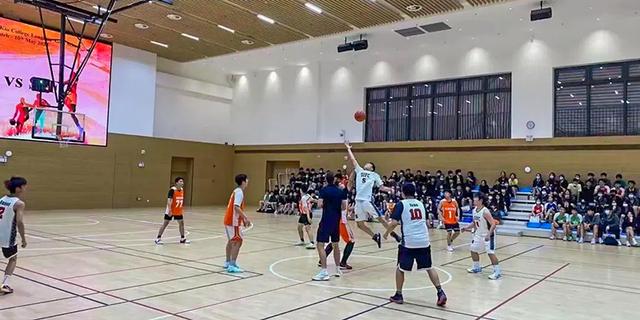 Students playing an indoor basketball game in a large gymnasium at Shenzhen College of International Education.