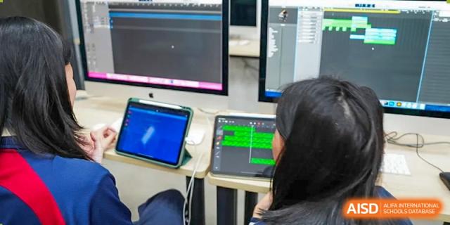 A female student working on an Apple desktop computer in a coding or design class at Shenzhen International Foundation College (SIFC).