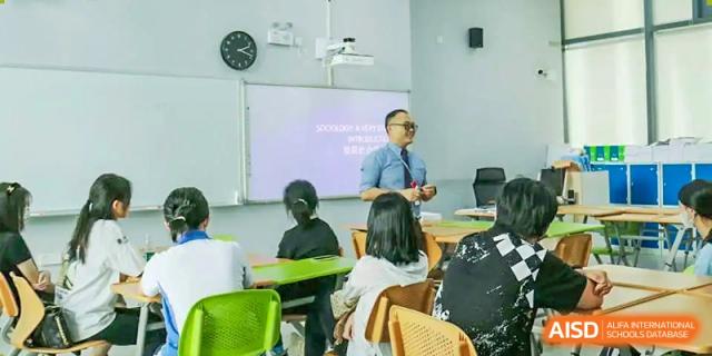 A teacher lecturing to a small group of students seated in a classroom with a whiteboard at Shenzhen International Foundation College (SIFC).