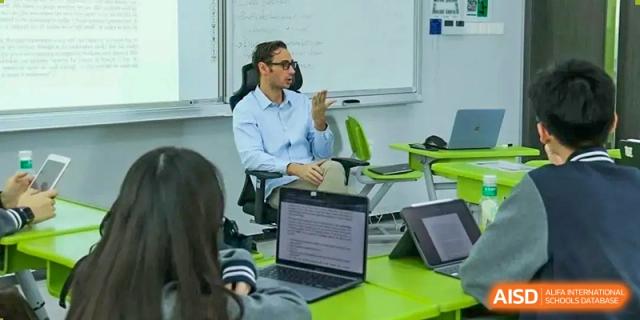 A student or teacher working on a laptop in a modern classroom or office setting at Shenzhen International Foundation College (SIFC).