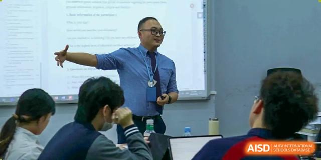 A teacher lecturing and using a smart board to explain a concept to students in a classroom at Shenzhen International Foundation College (SIFC).
