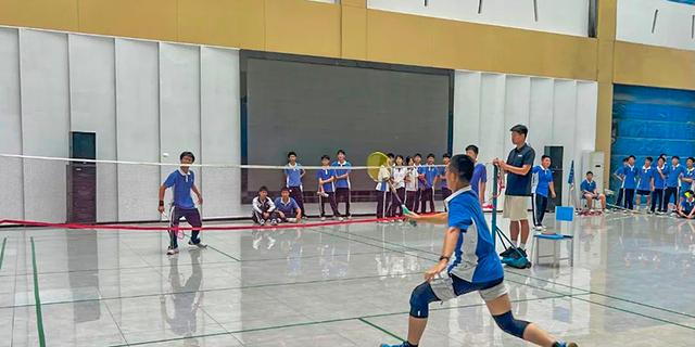 A student preparing to serve or receive the ball during an indoor volleyball or badminton game at Shenzhen International Foundation College (SIFC).