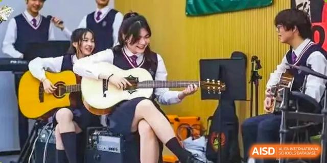 A female student wearing a school uniform and playing an acoustic guitar at Shenzhen International Foundation College (SIFC).