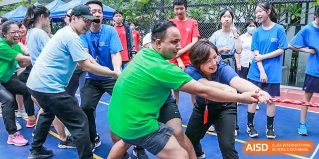 Students and a teacher participating in a team-building or tug-of-war outdoor activity at Shenzhen International Foundation College (SIFC).