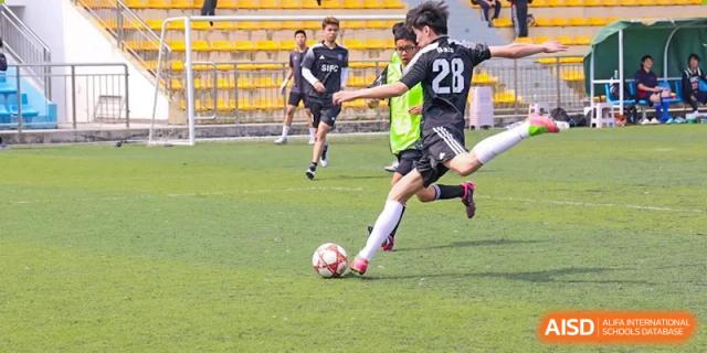 A close-up of a student playing soccer on a grassy field at Shenzhen International Foundation College (SIFC).