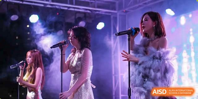 A student singing into a microphone on a stage with purple lighting during a performance at Shenzhen International Foundation College (SIFC).