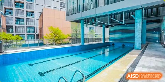 An outdoor swimming pool surrounded by a fence and greenery at Shenzhen International Foundation College (SIFC).