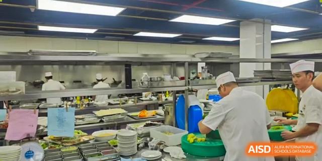 A busy scene inside a clean, commercial kitchen where school meals are being prepared at Shenzhen International Foundation College (SIFC).