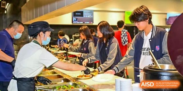 Students serving themselves from a buffet line with hot food during a meal at Shenzhen International Foundation College (SIFC).